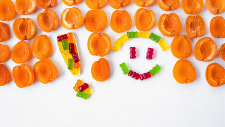 Bright candies and dried apricots form a playful smiley face design.の素材