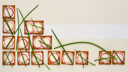 A colorful display of crisp snacks topped with radish and chives artistically placed.の素材