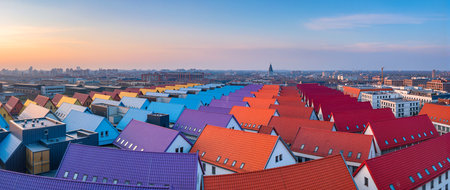 Rows of brightly colored rooftops reflect the warm glow of the sunset over the city.の素材
