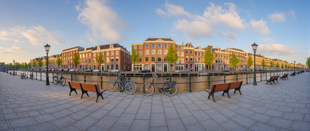 Vibrant sunset over Amsterdam's canals with bicycles parked near benches along the water.の素材