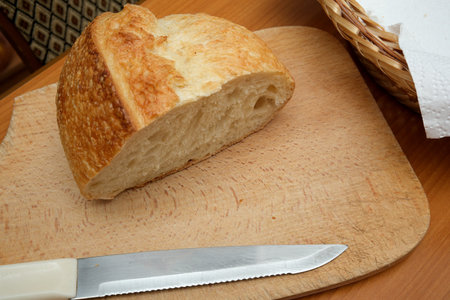 A loaf of crusty bread rests on a wooden board, ready for slicing and sharing.