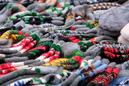 Vibrant and cozy mittens are spread out at a bustling winter market stall.の写真素材