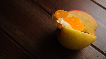 Bright fruits rest in a carved apple on a rustic wooden surface, inviting joy.の写真素材