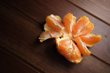 Bright mandarin sits open, showing its sweet orange segments on rustic wood.の写真素材