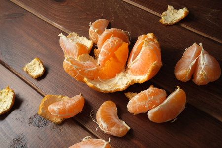 Sweet orange segments rest on a warm wooden background, inviting a tasty snack.の写真素材
