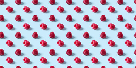 Rows of fresh raspberries display their vibrant red color against a soft blue backdrop.の素材