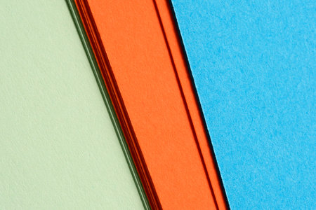 Sheets of colorful paper in shades of green, orange, and blue laid side by side.