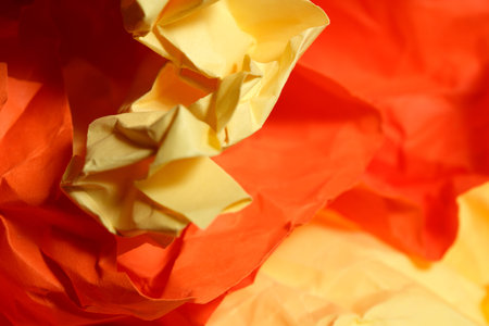 Crumpled yellow and orange paper forms create a vibrant and lively scene.