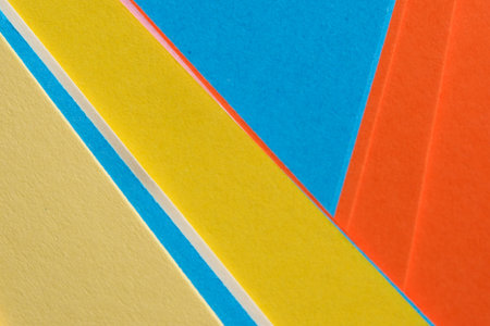 Bright sheets of paper in shades of blue, yellow, and orange display a cheerful design.