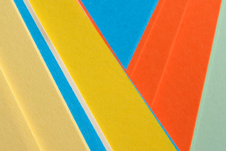 Colorful paper triangles in vibrant shades lay flat, forming an artistic arrangement.