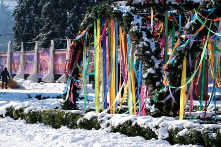 Bright ribbons dance in the cold breeze as snow blankets the festive park.