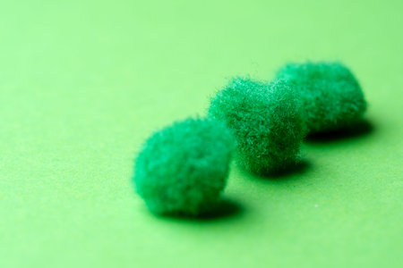 Three small fuzzy green forms sit on a bright green background, creating a playful scene.