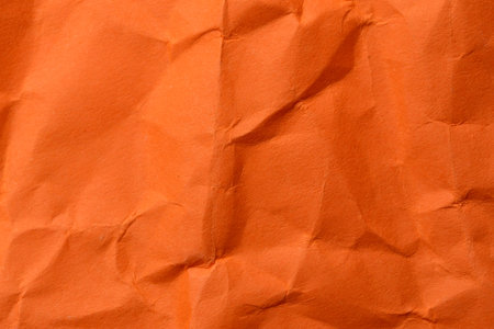 Crinkled orange paper creates a vibrant and dynamic background for art.の写真素材