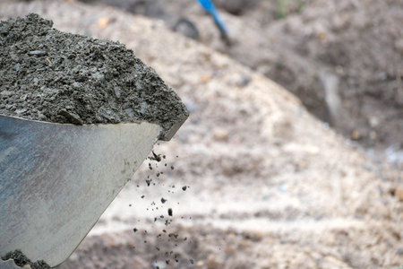 Concrete flows from a shovel, ready for building a solid foundation and structure.
