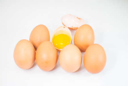 Six whole brown eggs and broken half one.の写真素材