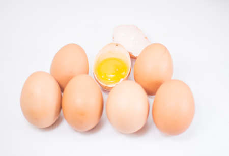 Six whole brown eggs and broken half one.の写真素材