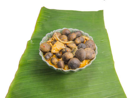 Red curry chicken in coconut milk with puff ball earthstars mushroom and bamboo shoot in green bowl put on banana leaf. isolated on white background.の写真素材