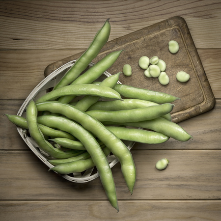 Broad bean pods and seeds on wood cutting board. Wood background. Top view.の写真素材