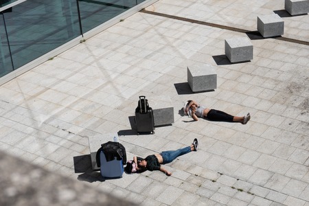 Santiago de Compostela, Spain. April 28 2019: Two traveler girl lying on paving stone waiting and having a sun bathの写真素材