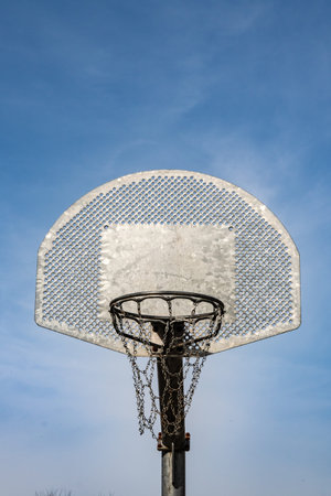 Metallic basketball board and hoop with blue sky in the background
