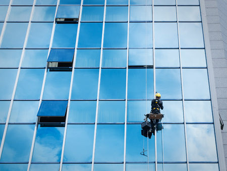 Window cleaner working on a glass facade suspended. Heavy work conceptの写真素材
