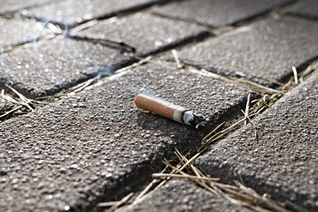 Smoking concept. Burning Cigarette end on paving stoneの写真素材