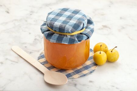 Pot of plum jam and fruit on white marble. Preserved fruitsの写真素材