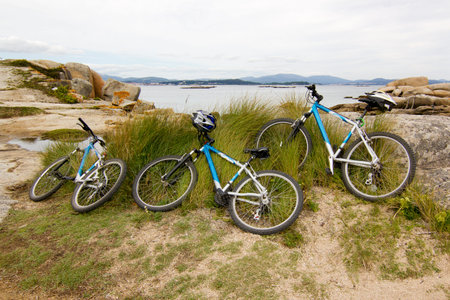 Three bike lying on the beach with atlantic ocean coastline at background. Family leisure concept....
