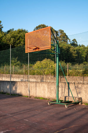 Outdoor basketball hoop with blue sky and trees at the background. City basketball court. Copy space