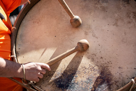 Musician hands with drum sticks playing a bass drum during an outdoor festival. Spanish culture