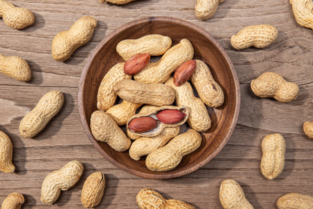 Peanuts in bowl on rustic wooden table. Arachis hypogaea