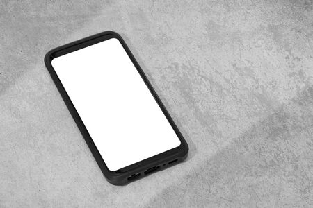 Smart phone with white screen isolated on textured concrete background. Mock up template. Copy spaceの写真素材
