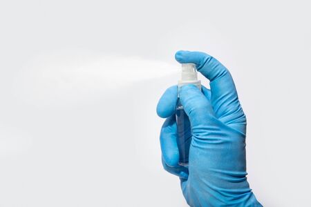 Hand in protective glove spraying alcohol or cleanser. Disinfection or hygiene concept on outbreak. White background. Copy spaceの写真素材