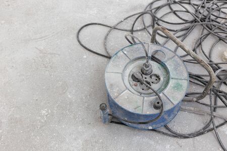Dirty Electrical extension cord or cable spool with plugs on construction site. Tangled electrical wire. Copy spaceの写真素材