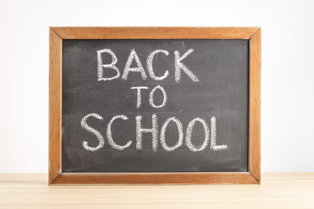 Back to school concept. Chalkboard with handwritten text on table