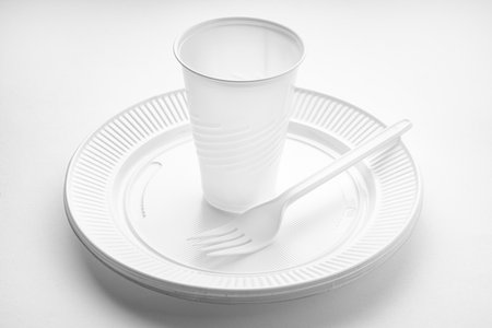 Plastic dishware. White vase, plate and fork on white background. Disposable plastic wasteの写真素材