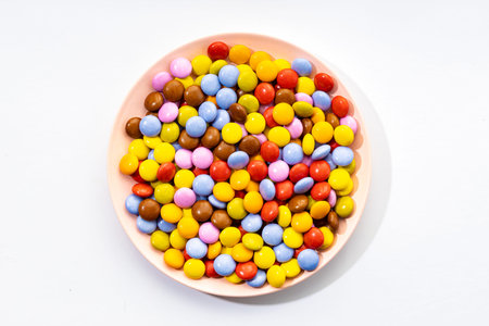 Multicolored Chocolate candy in plate on white background. Top view