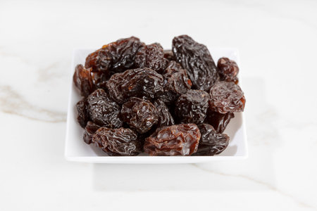 Close up of Raisins on plate isolated on White marble Background. Dried grapeの写真素材