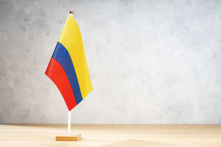 Colombia table flag on white textured wall. Copy space for text, designs or drawingsの写真素材