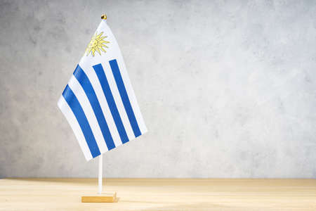 Uruguay table flag on white textured wall. Copy space for text, designs or drawingsの写真素材