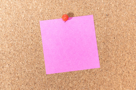 Blank pink note and push pin on cork board. Template to ad text or drawings