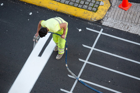 Galicia, Spain; december 16, 2021: Worker painting a pedestrian crosswalk using paint sprayer gunのeditorial素材