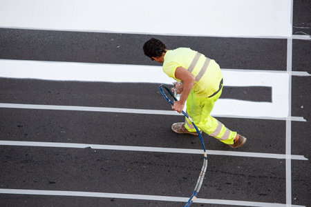 Galicia, Spain; december 16, 2021: Road painter worker painting lines of a zebra crossing using paint sprayer gunのeditorial素材