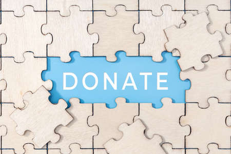 Donate word on blue background surrounded by puzzle piecesの写真素材