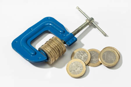 Euro Financial, money, tax pressure concept. Clamp clamping down of a group of euro coins on white backgroundの写真素材