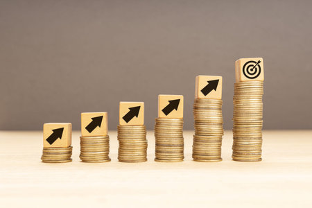 Business or wealth achievement goal concept. Stacking coins and wooden blocks with arrows and goal target icon. Copy spaceの写真素材