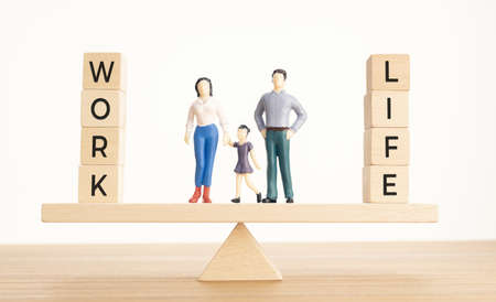 Balance Between Life And Work concept. Family figurines and Wooden blocks with word on Seesawの写真素材