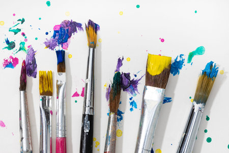 Group of Art Paint brushes and colorful splatter on white canvas paper. Close up