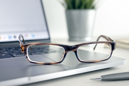 Close up of Eyeglasses on modern laptop on desk. Eye health and vision using computer and modern screen devicesの写真素材