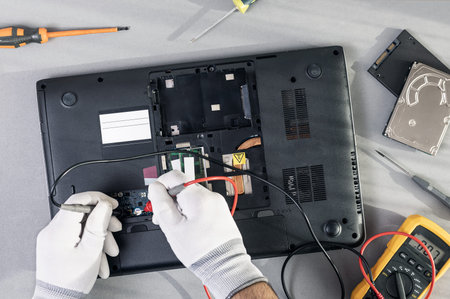 Technician hands repairing a laptop computer. Top view